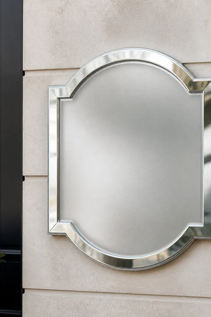 A mirror silver sign where the lettering area looks slightly softened, like a frosted insert. The mirror border reflects light, but the center looks diffused.