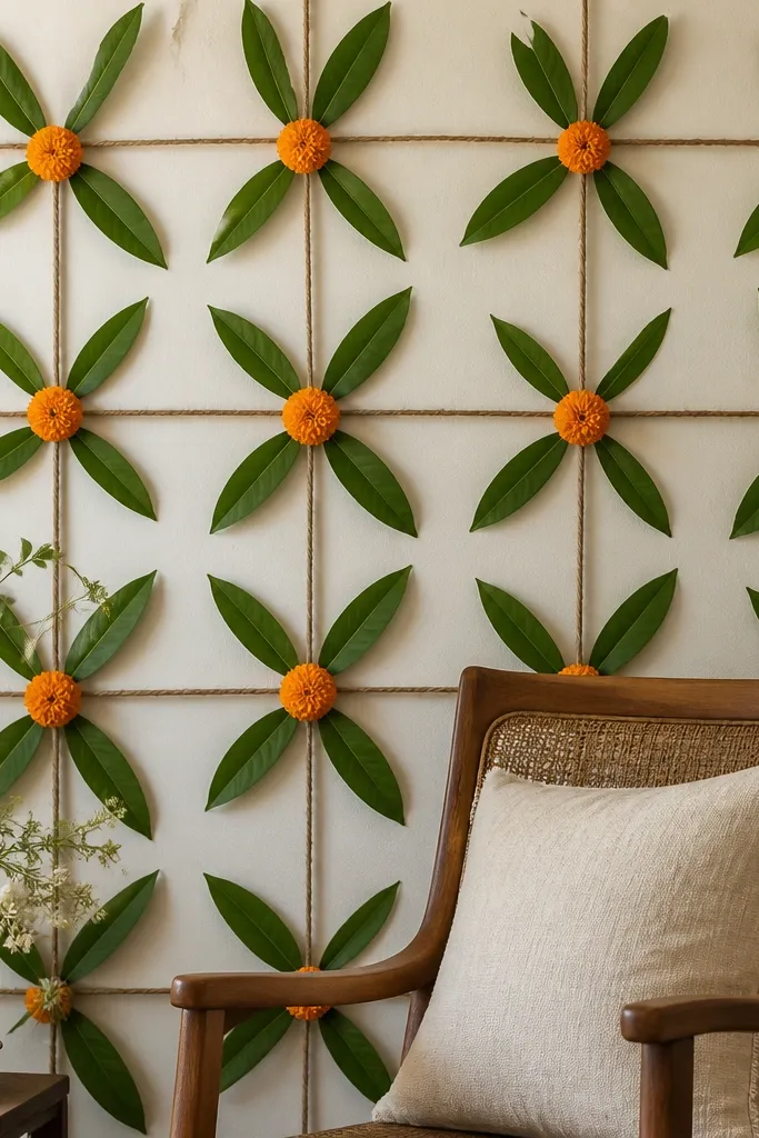 A wall section behind the chair covered with a simple jute string grid. Mango leaves are clipped and tucked into the intersections, creating a leafy pattern. A few marigold blossoms are placed at the center.