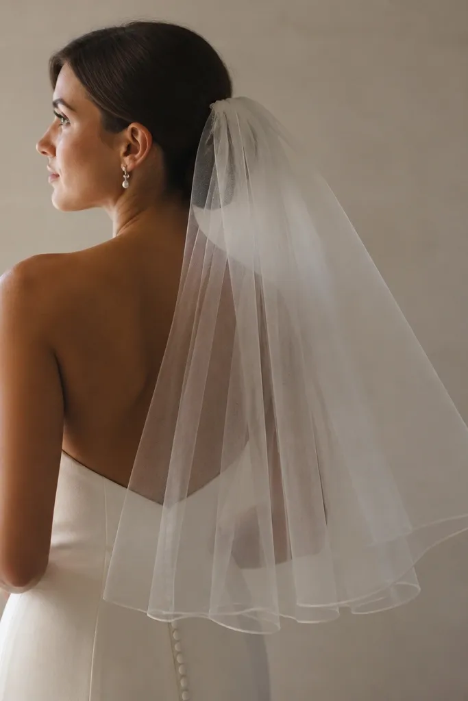 A simple tulle veil attached with a comb, falling to mid-back. The veil has soft movement and doesn't cover the eyes.